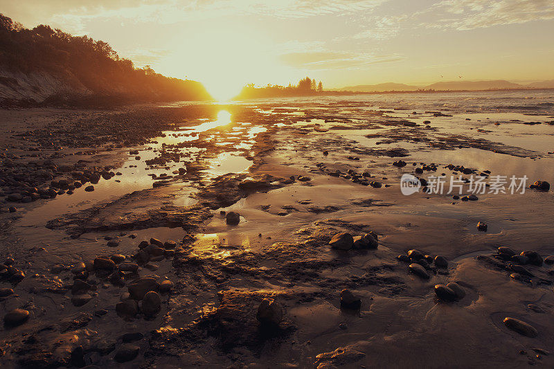 Sunset and rocks at the beach at Byron Bay